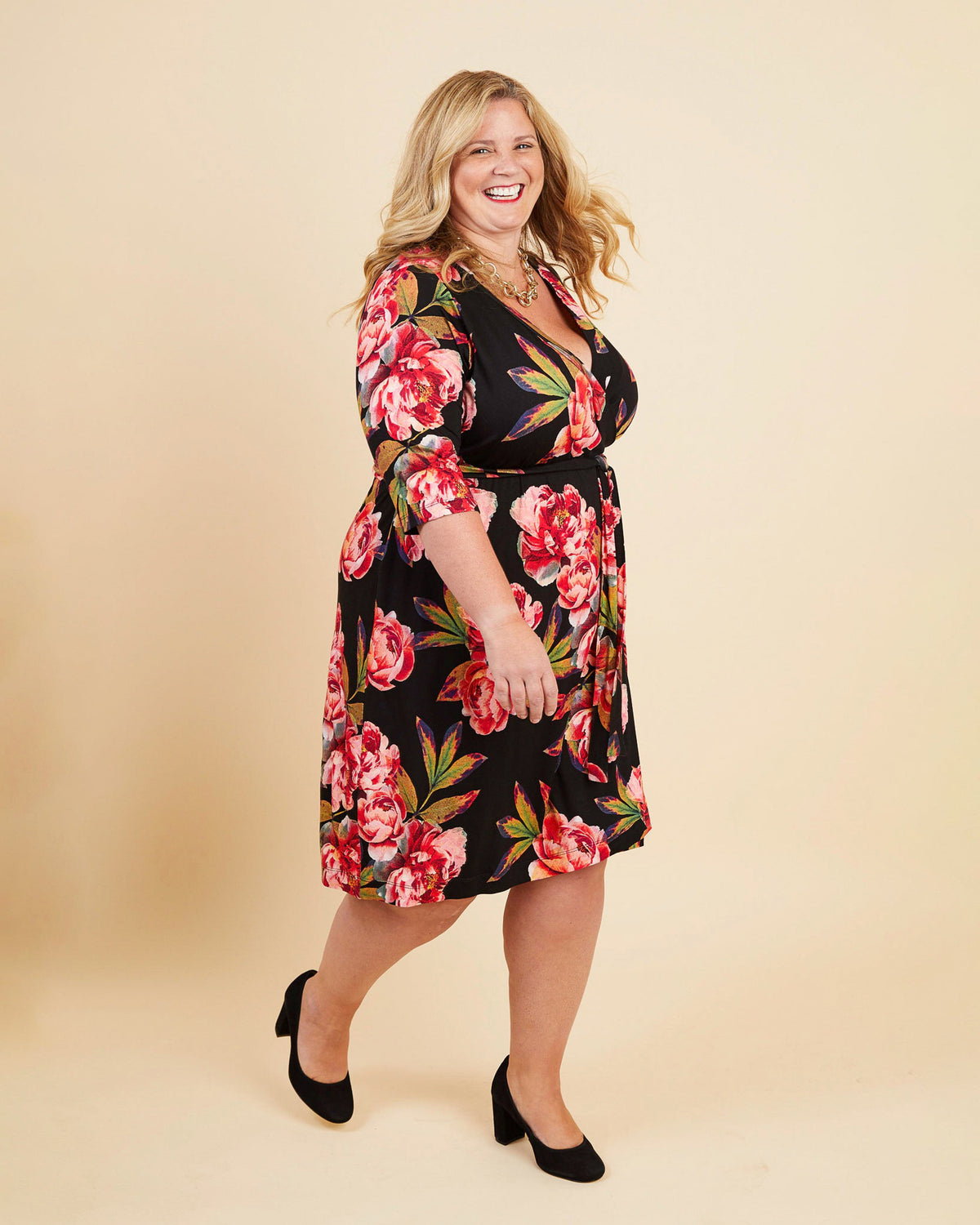 Woman wearing a floral dress on a beige background. This dress is the Appleton Wrap Dress sewing pattern from Cashmerette.
