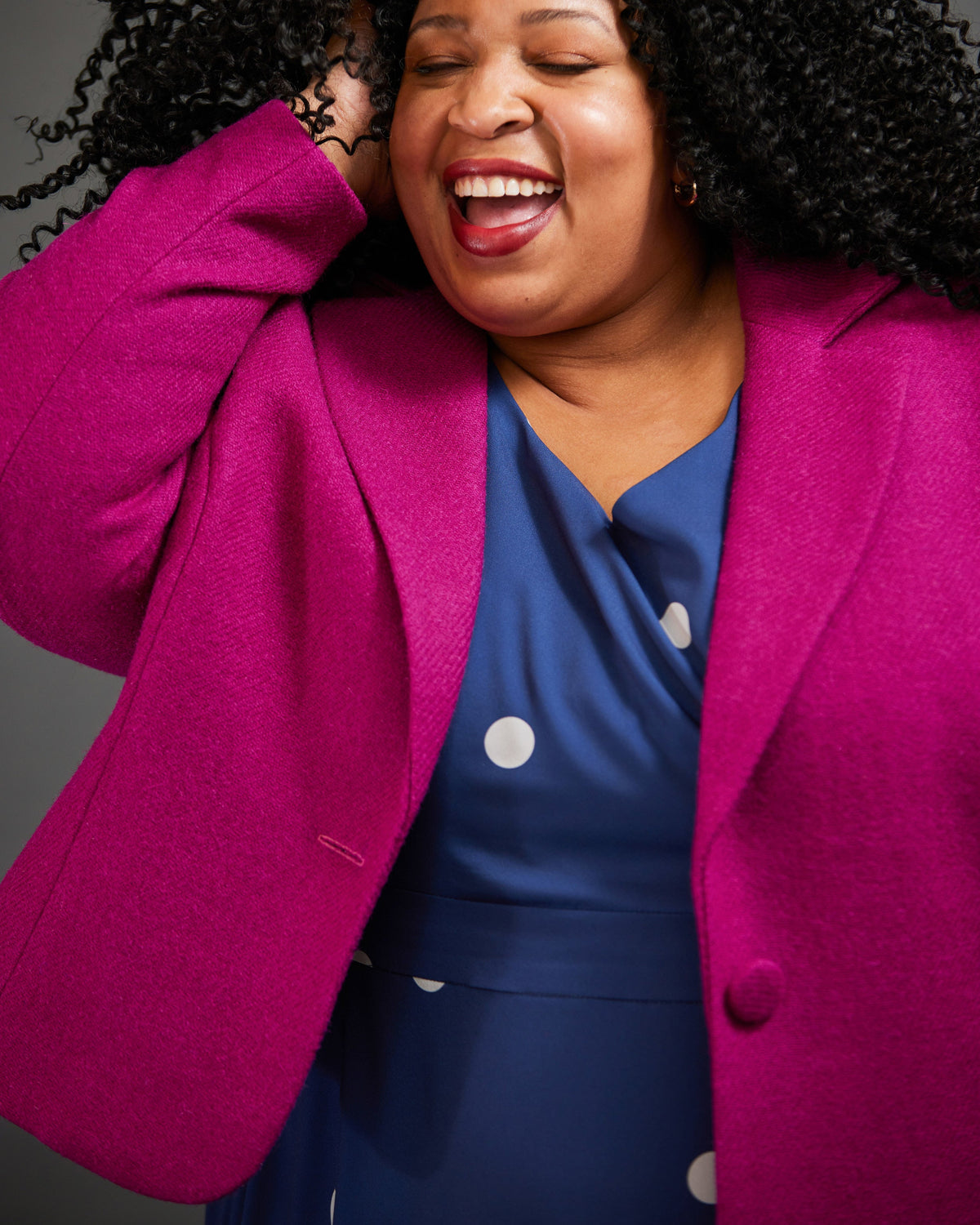 Woman wearing a bright pink blazer over a blue dress with white polka dots. This blazer is the Auburn Blazer sewing pattern from Cashmerette.