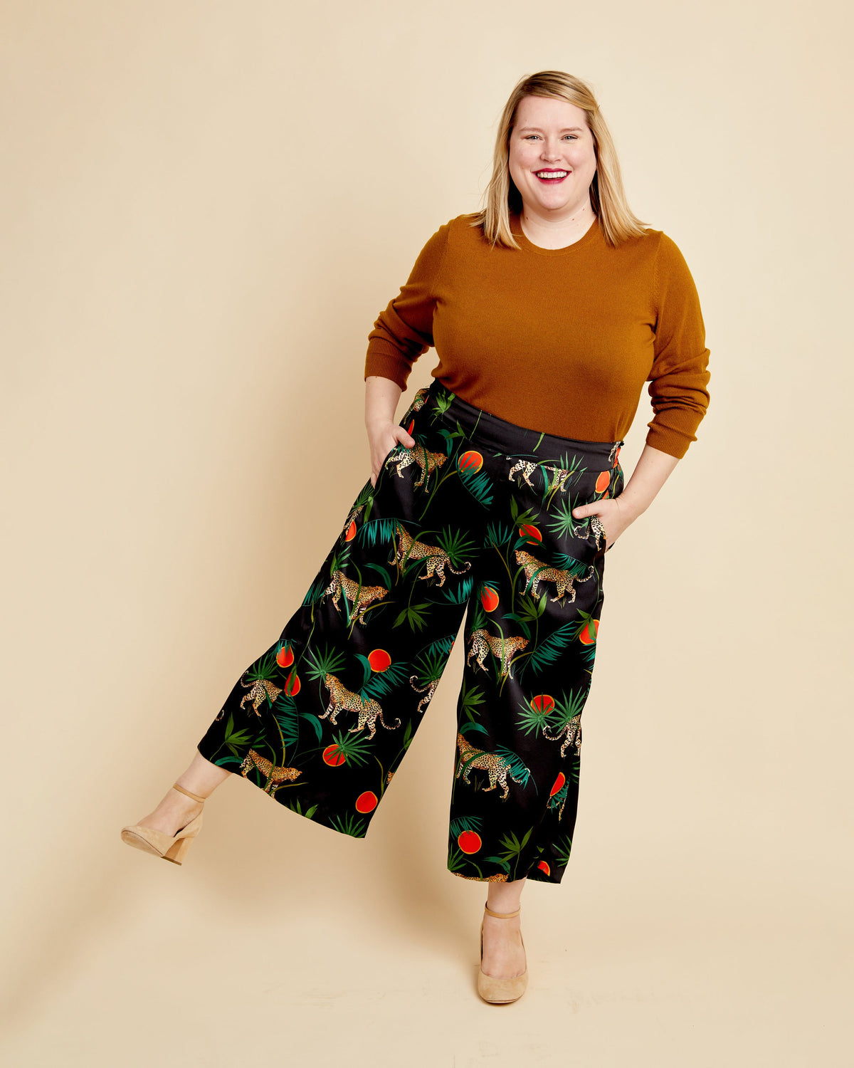 Woman wearing a brown sweater and patterned pants on a beige background. These pants are the Calder Pants & Shorts sewing pattern from Cashmerette.