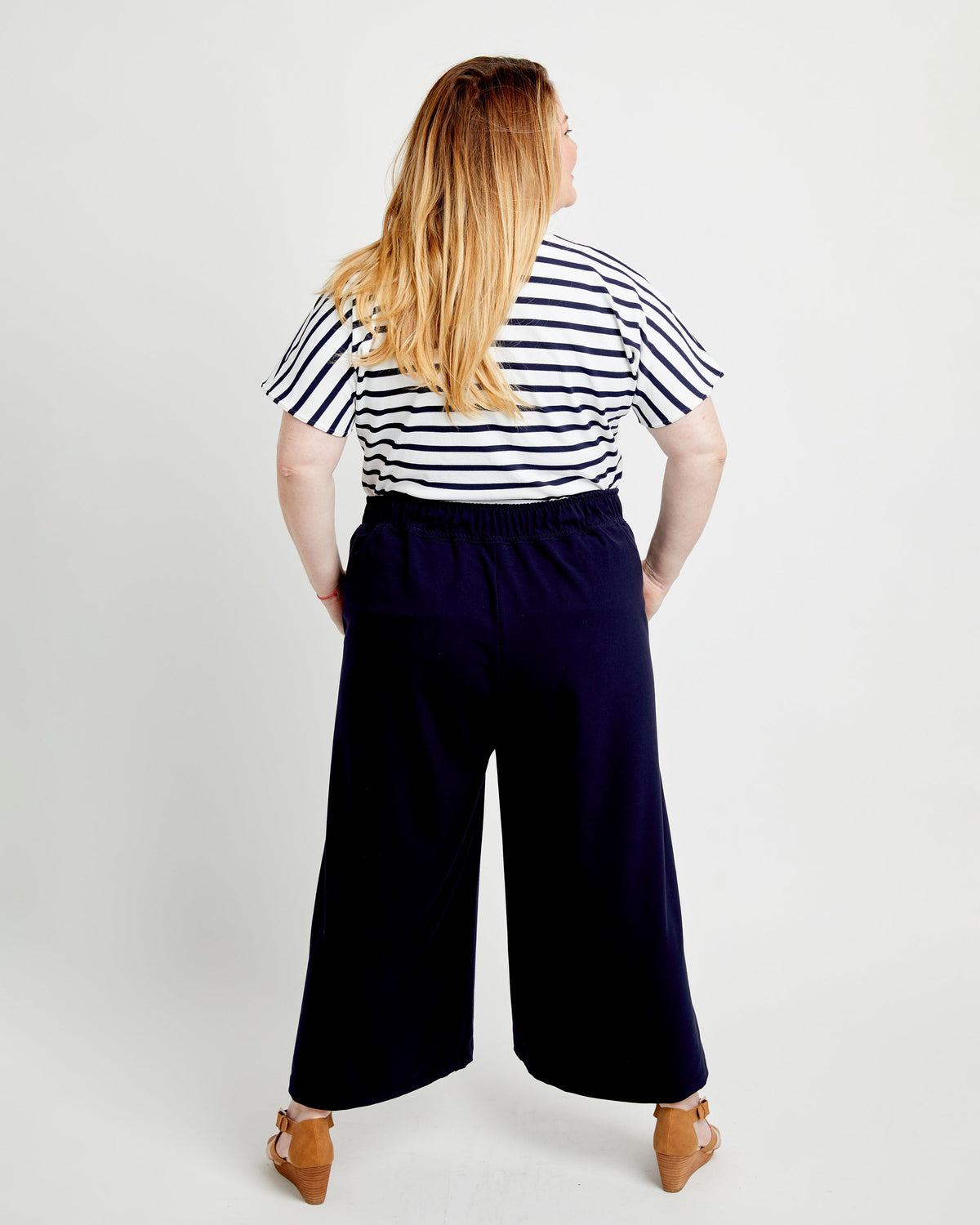Person wearing a striped shirt and wide-leg pants on a white background. These pants are the Calder Pants & Shorts sewing pattern from Cashmerette.