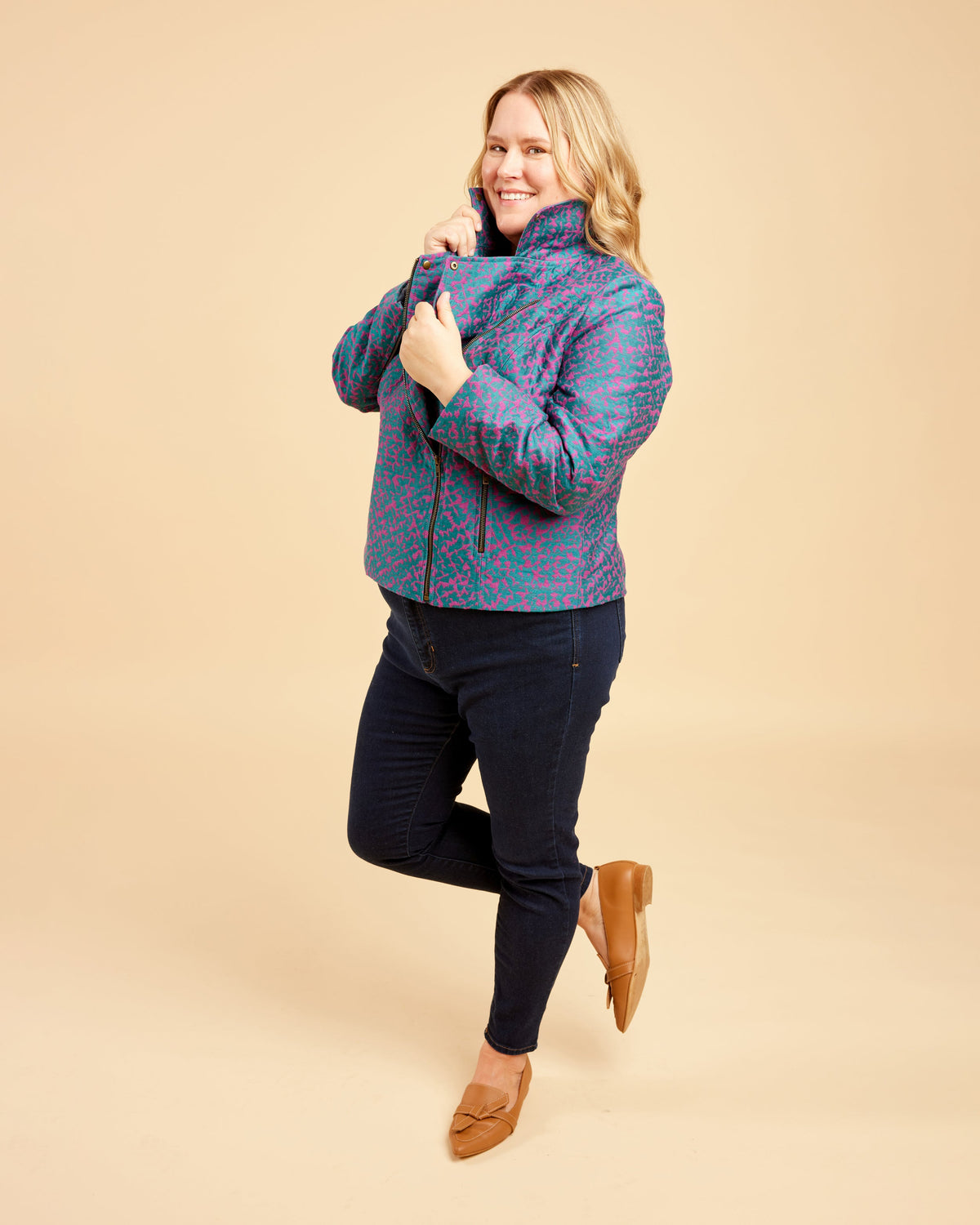 Woman wearing a patterned jacket on a beige background. This biker jacket is the Canton Moto Jacket sewing pattern from Cashmerette.