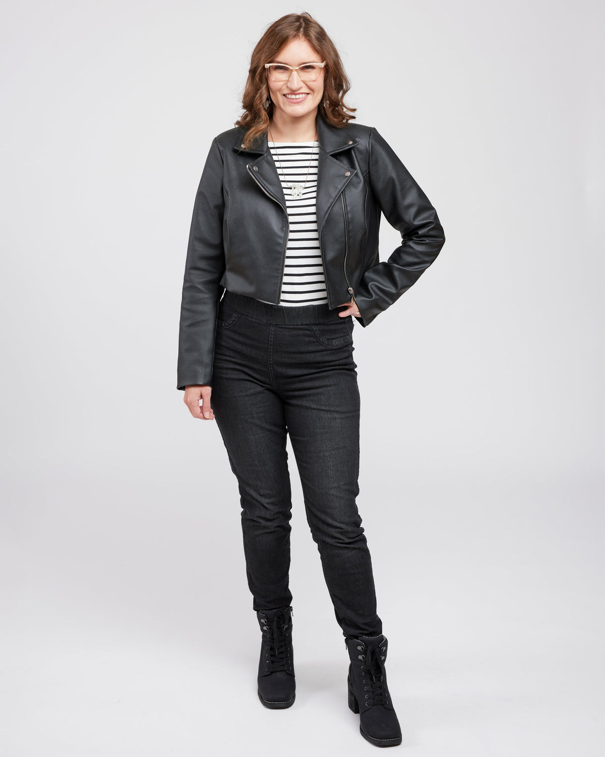 Woman wearing a black leather jacket in front of a white wall. This biker jacket is the Canton Moto Jacket sewing pattern from Cashmerette.