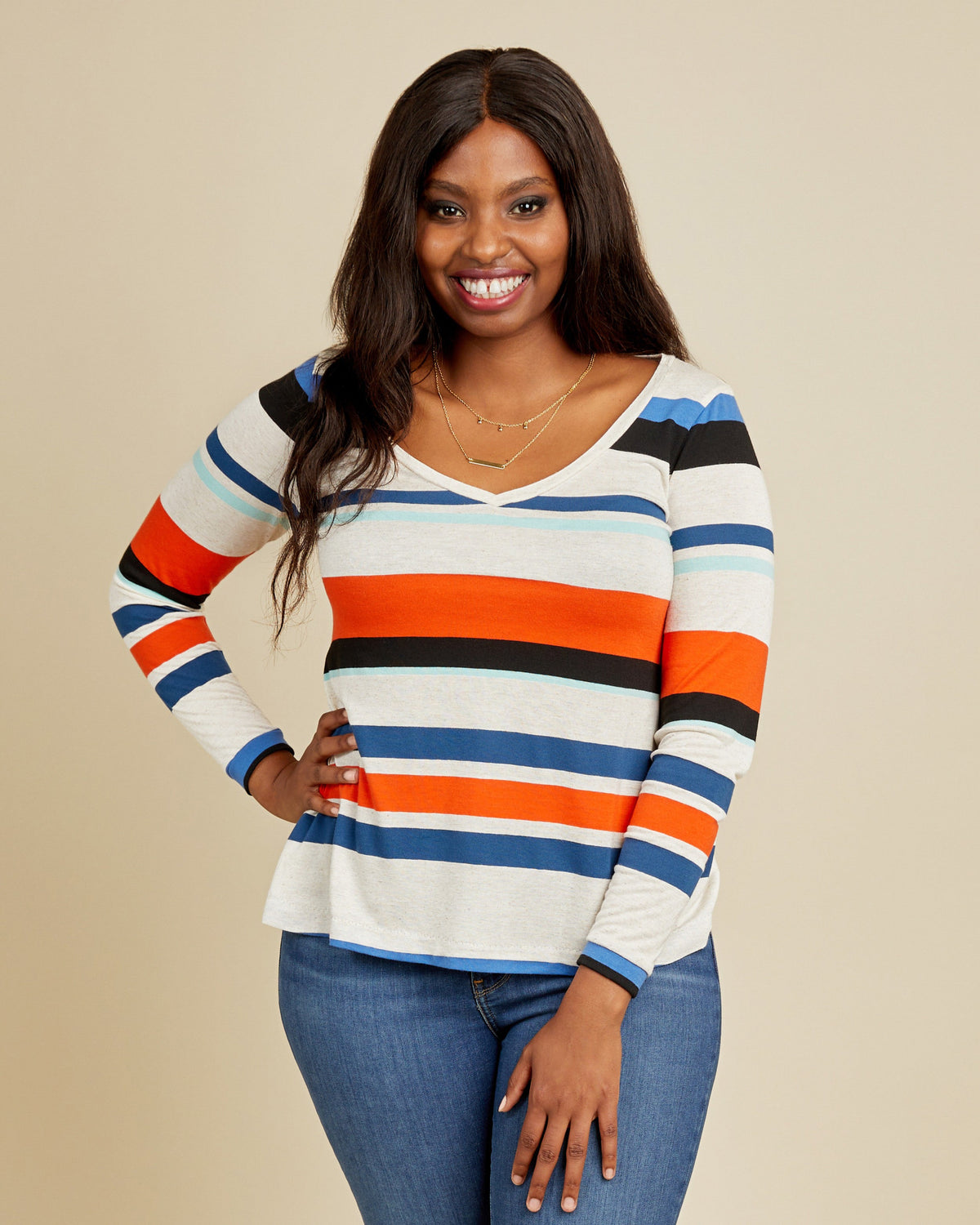 Woman wearing a colorful striped sweater against a beige background. This t-shirt is the Concord T-Shirt sewing pattern from Cashmerette.