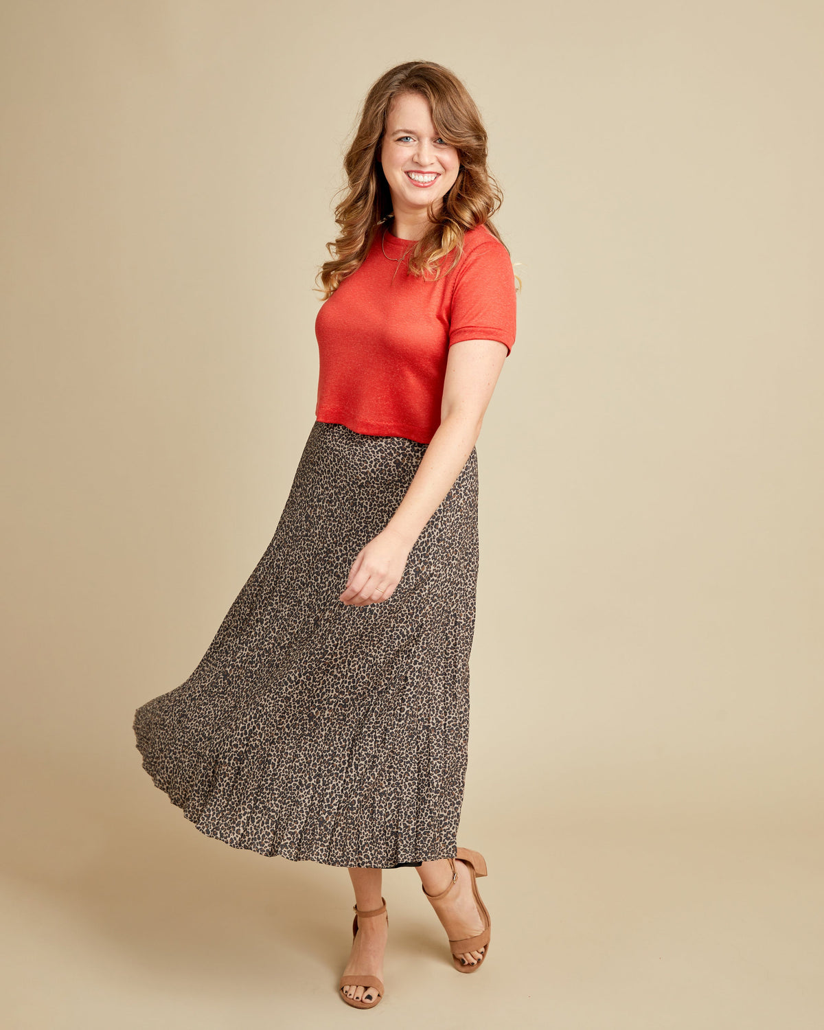 Woman wearing a red top and patterned skirt on a beige background. This t-shirt is the Concord T-Shirt sewing pattern from Cashmerette.