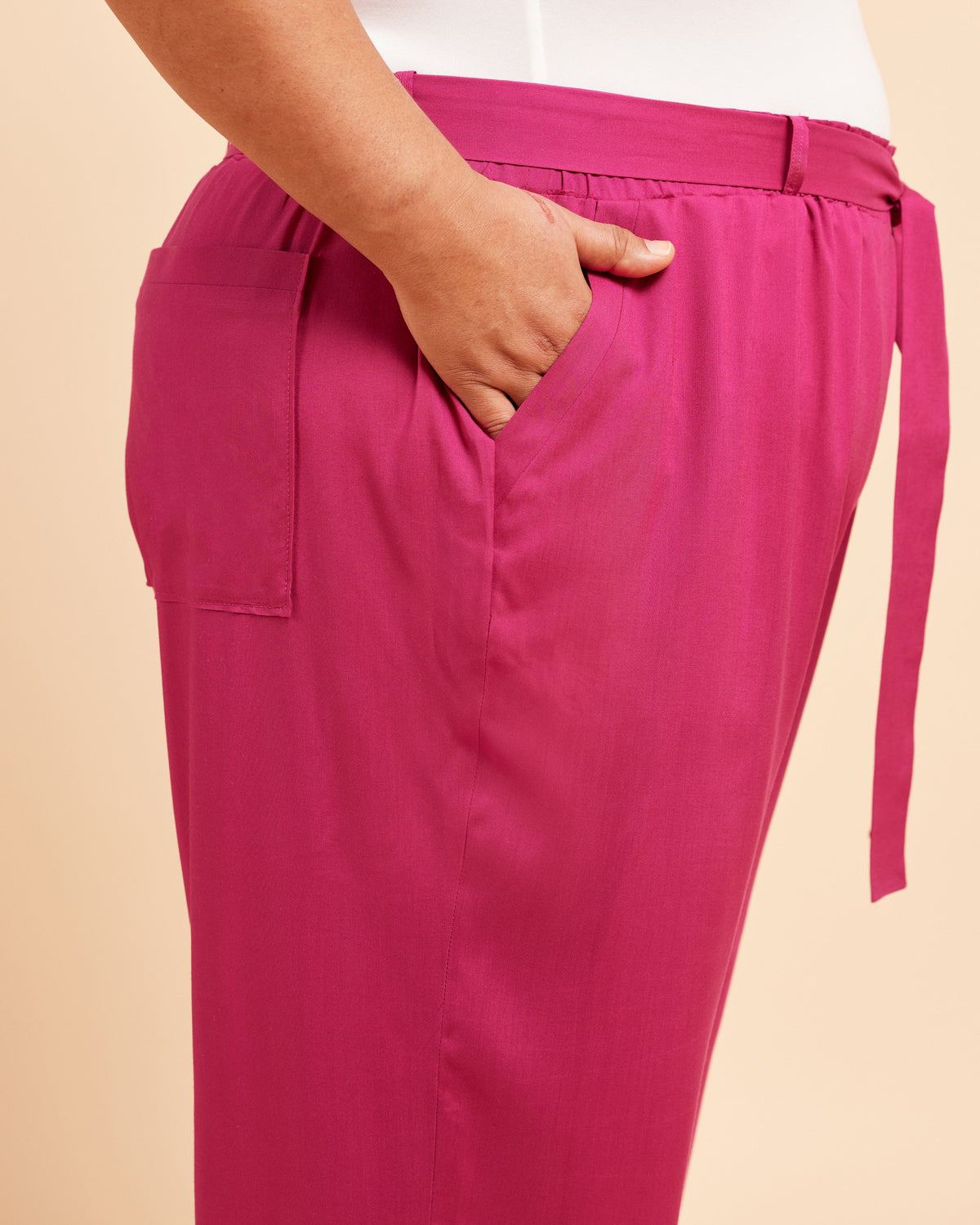 Pink pants with a belt on a beige background. These pants are the Everett Pants & Shorts sewing pattern from Cashmerette.