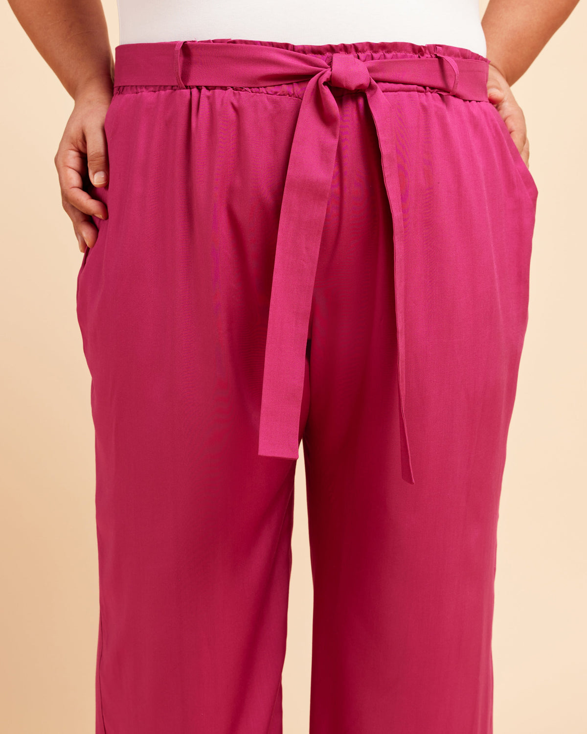 Pink pants with a tie waist on a beige background. These pants are the Everett Pants & Shorts sewing pattern from Cashmerette.
