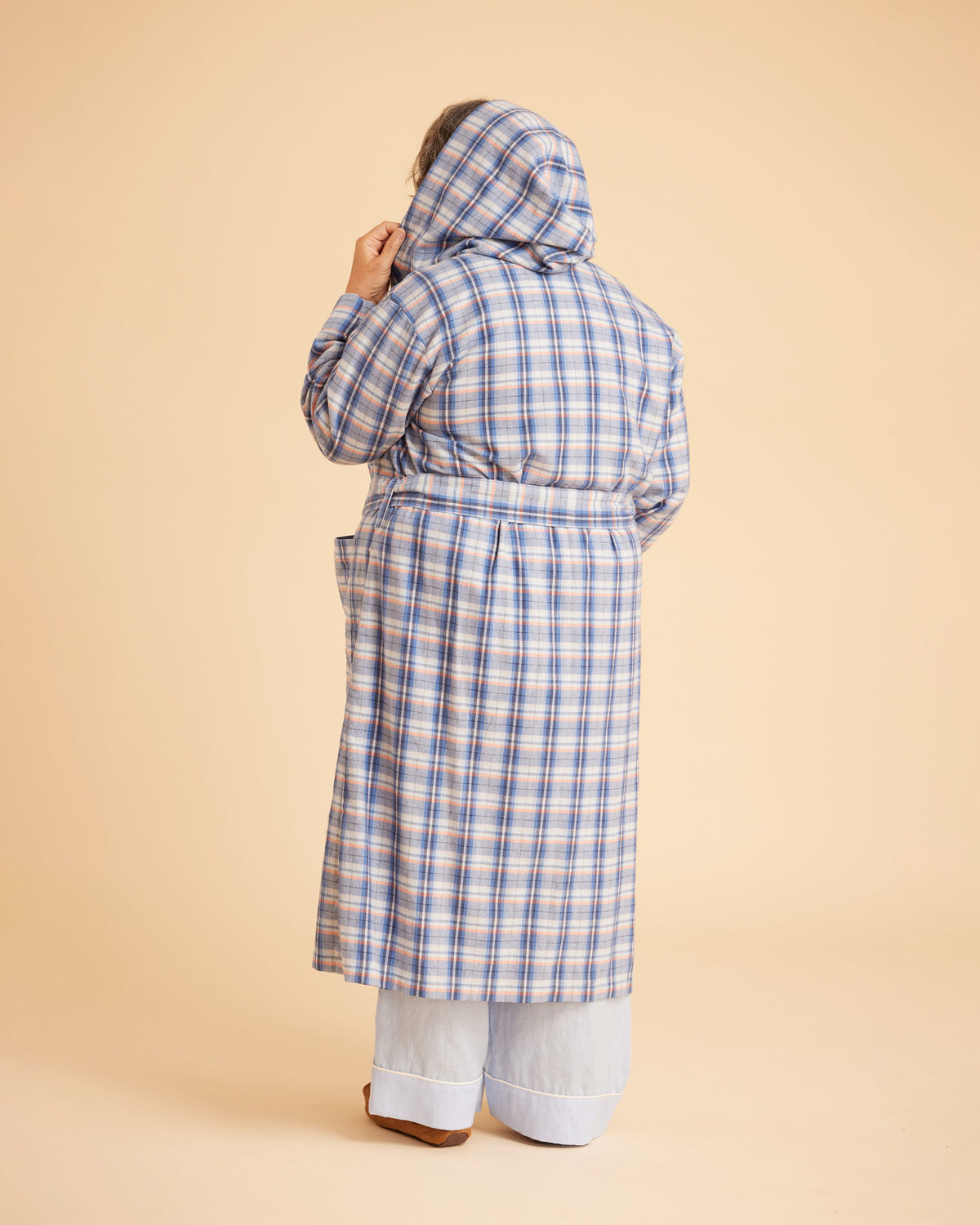 Person wearing a blue plaid coat on a beige background. This is the Fiske Sleepwear Set sewing pattern from Cashmerette.