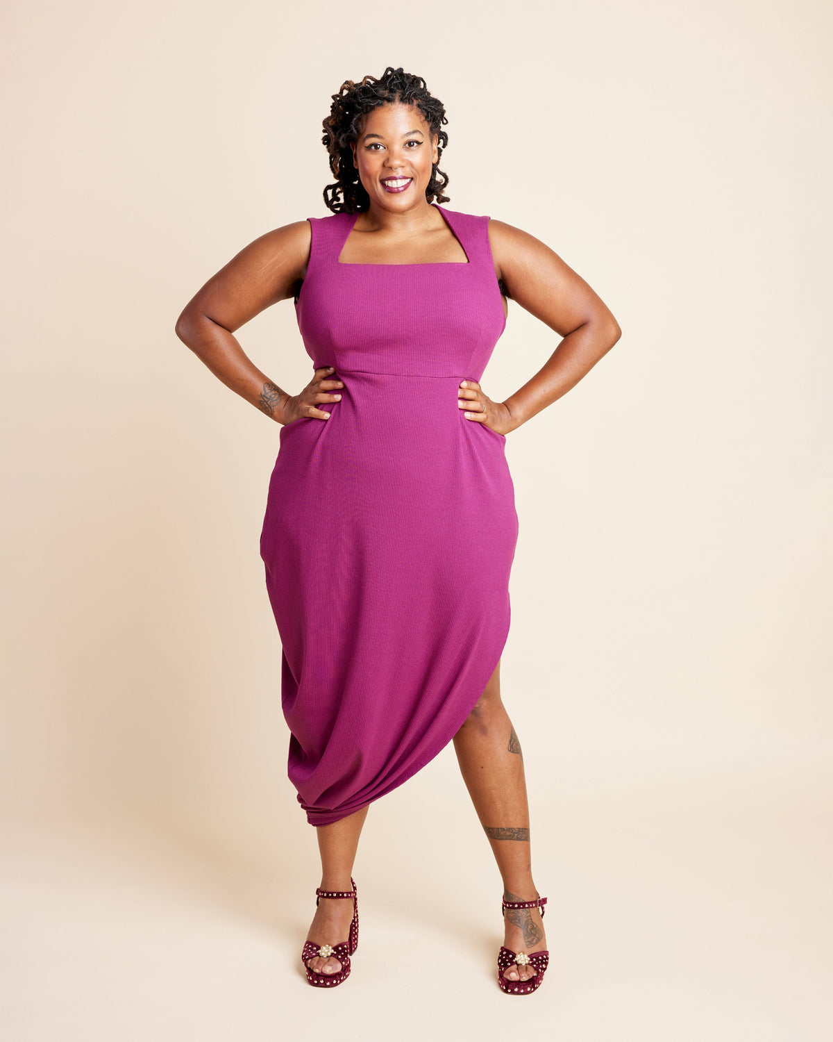 Woman wearing a magenta dress against a beige background. This is the Grafton Dress, Top & Skirt sewing pattern from Cashmerette.