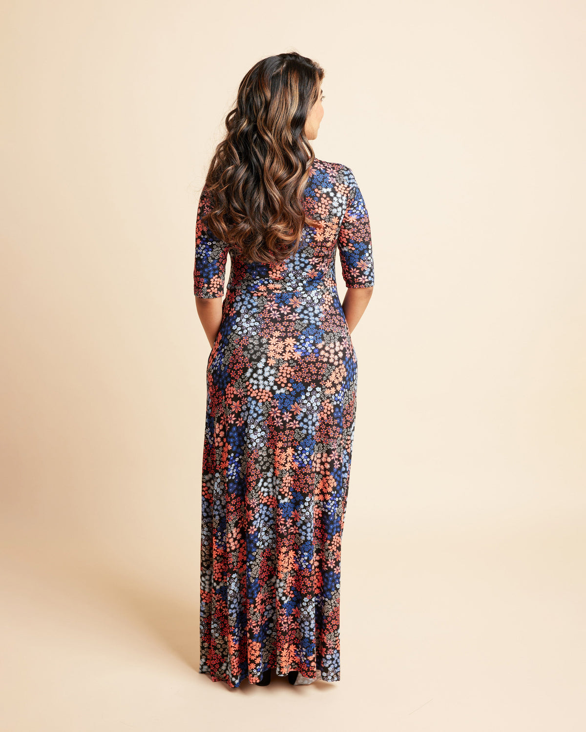 Woman wearing a floral dress on a beige background. This is the Grafton Dress, Top & Skirt sewing pattern from Cashmrette.