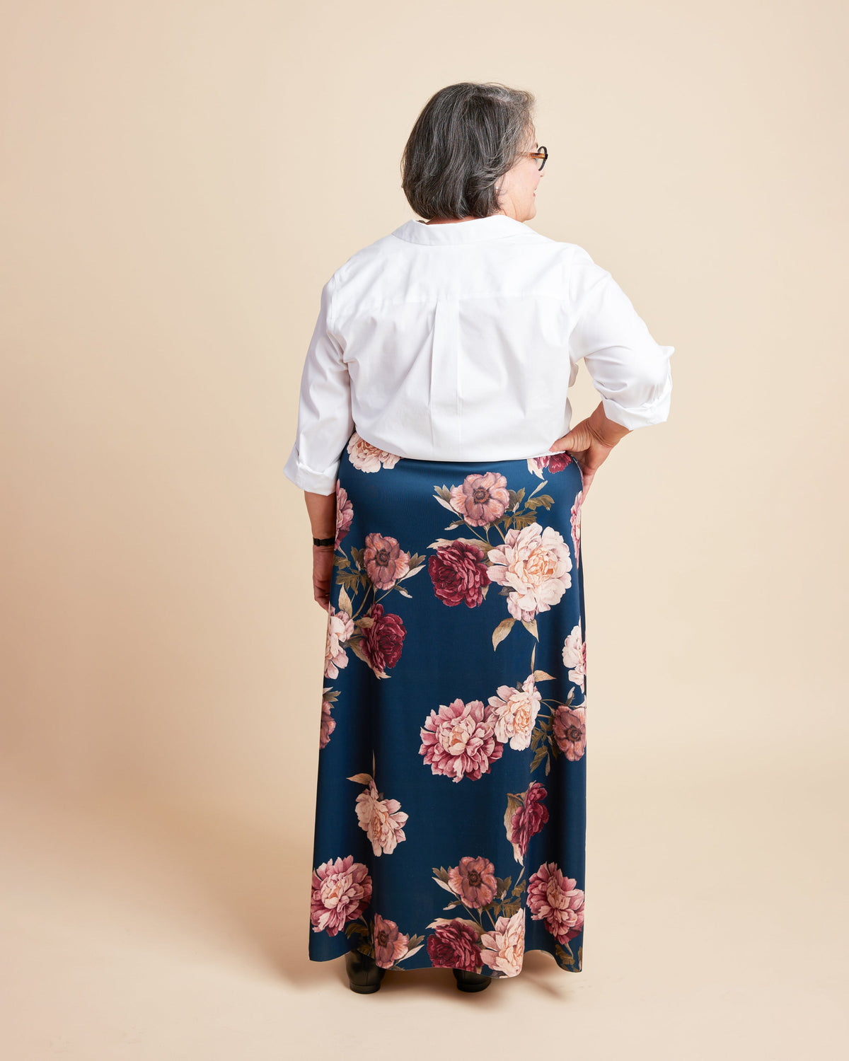 Person wearing a white blouse and floral skirt on a beige background. This is the Grafton Dress, Top & Skirt sewing pattern from Cashmerette.