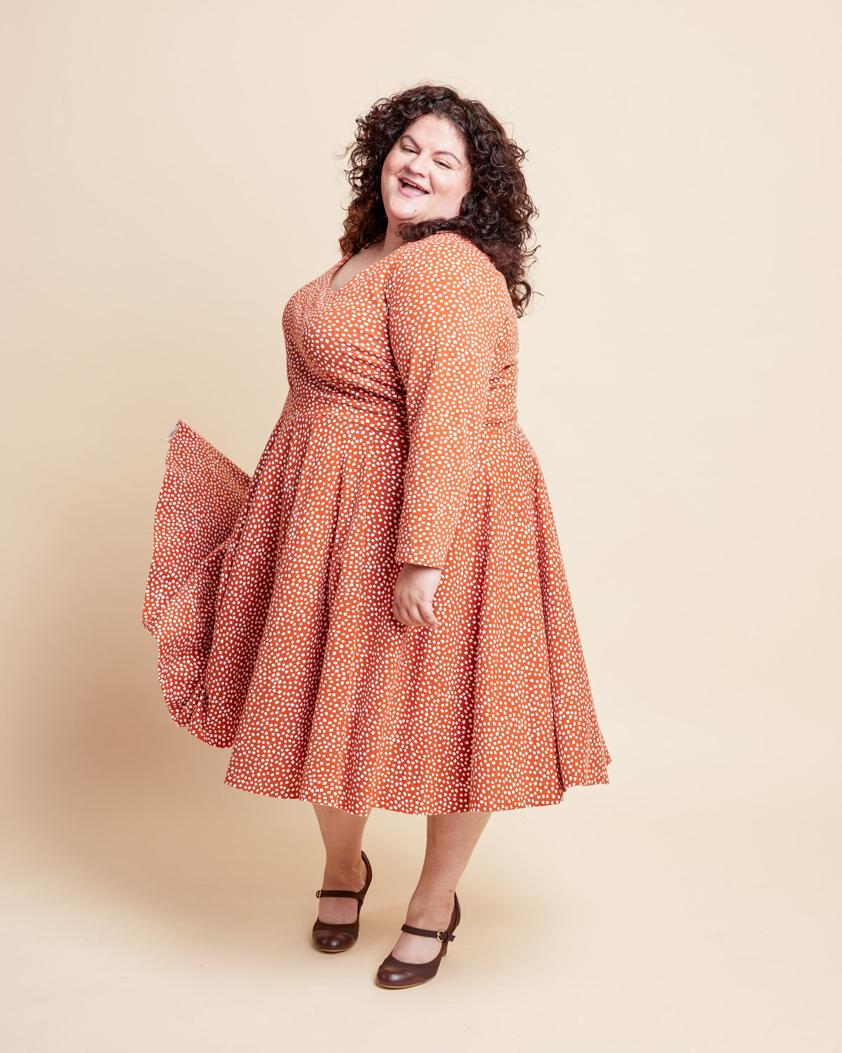 Woman wearing a red floral dress against a beige background. This is the Grafton Dress, Top & Skirt sewing pattern from Cashmerette.