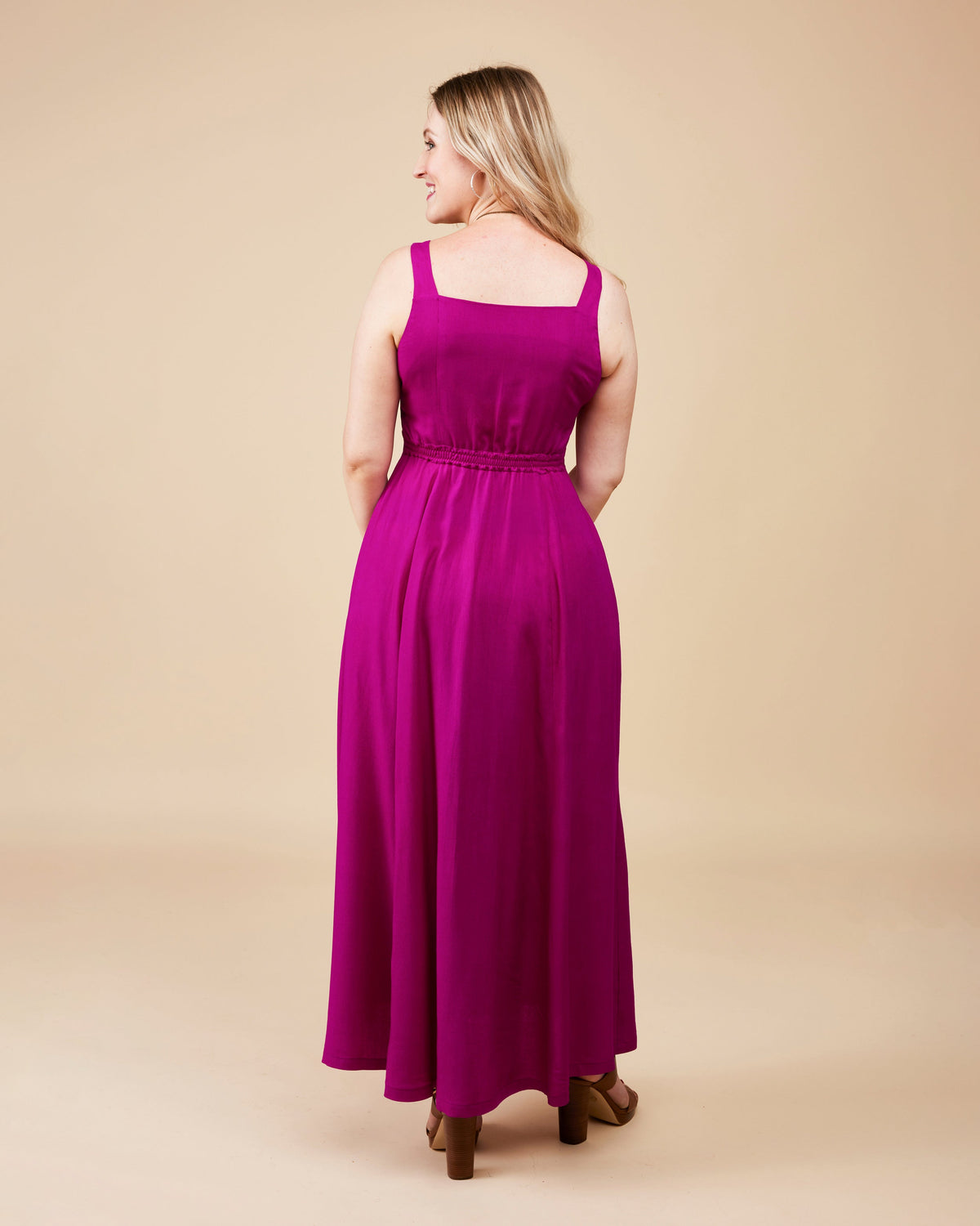 Woman wearing a long magenta dress on a beige background. This is the Holyoke Maxi Dress & Skirt sewing pattern from Cashmerette.
