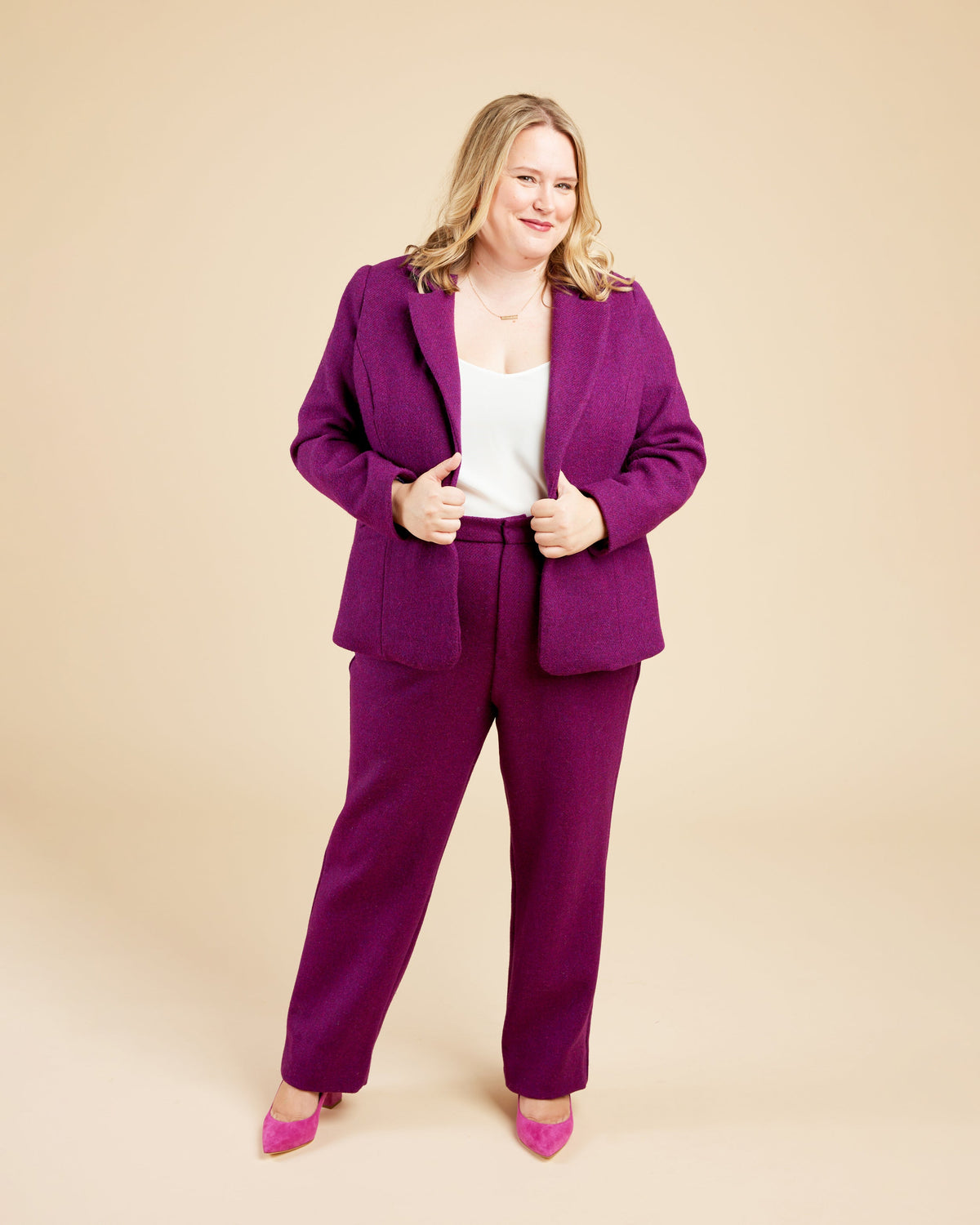 Woman wearing a purple suit on a beige background. These pants are the Meriam Trousers sewing pattern from Cashmerette.
