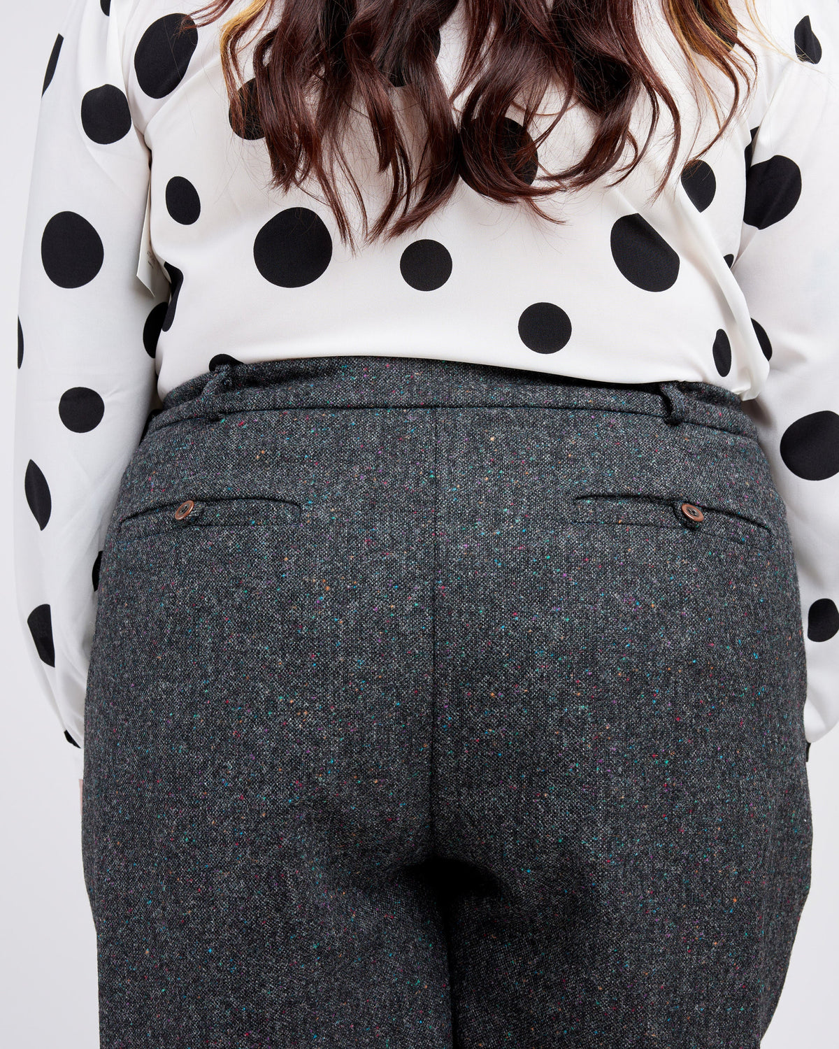 Person wearing a polka dot blouse and gray pants on a white background. These pants are the Meriam Trousers sewing pattern from Cashmerette.