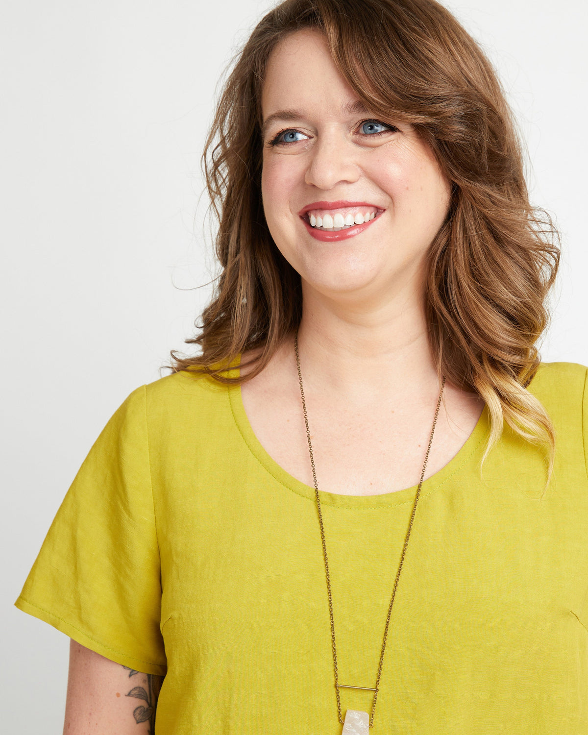 Woman wearing a yellow shirt with a plain background. This top is the Montrose Top sewing pattern from Cashmerette.