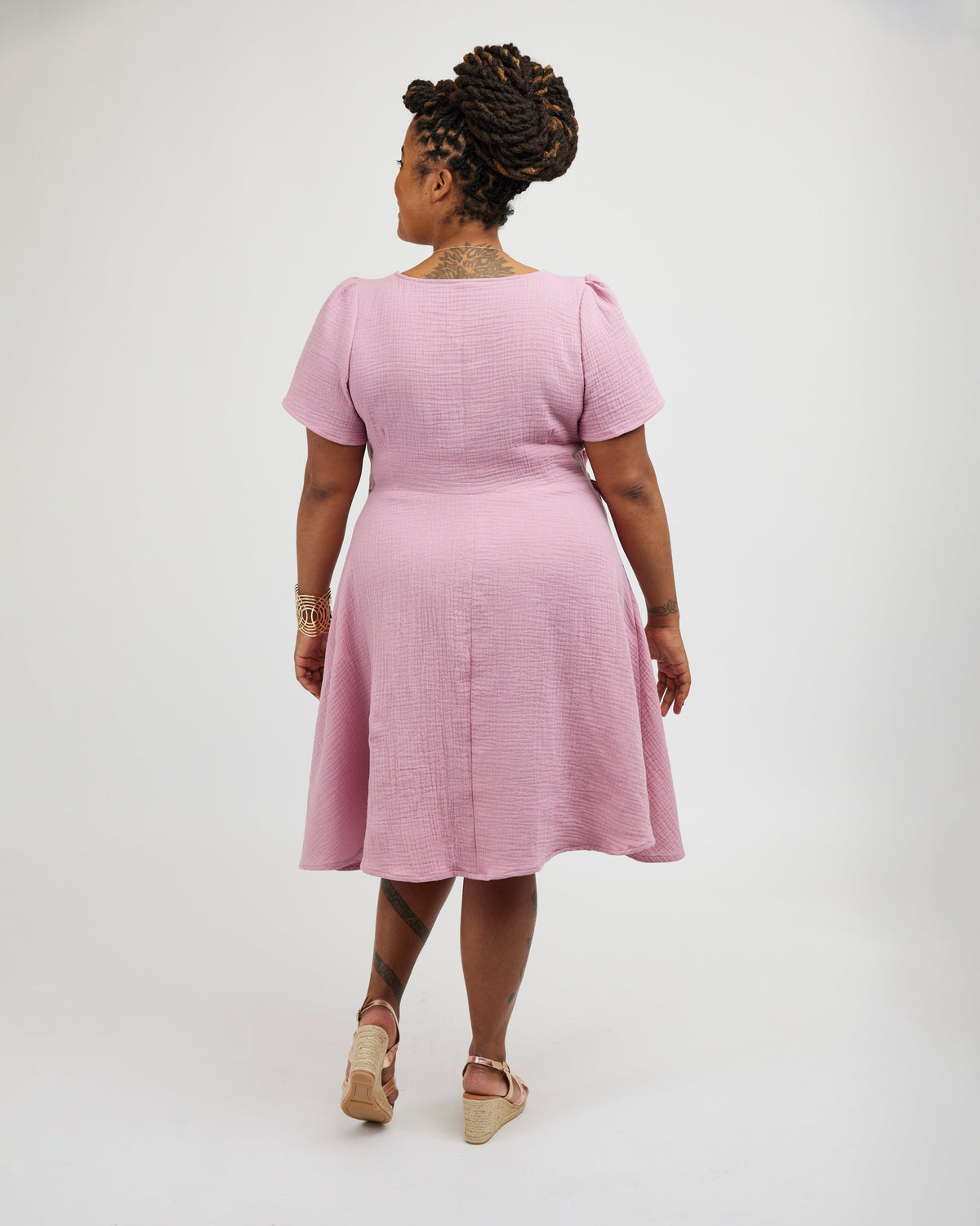 Woman wearing a pink dress on a white background. This dress is the Roseclair Wrap Dress sewing pattern from Cashmerette.