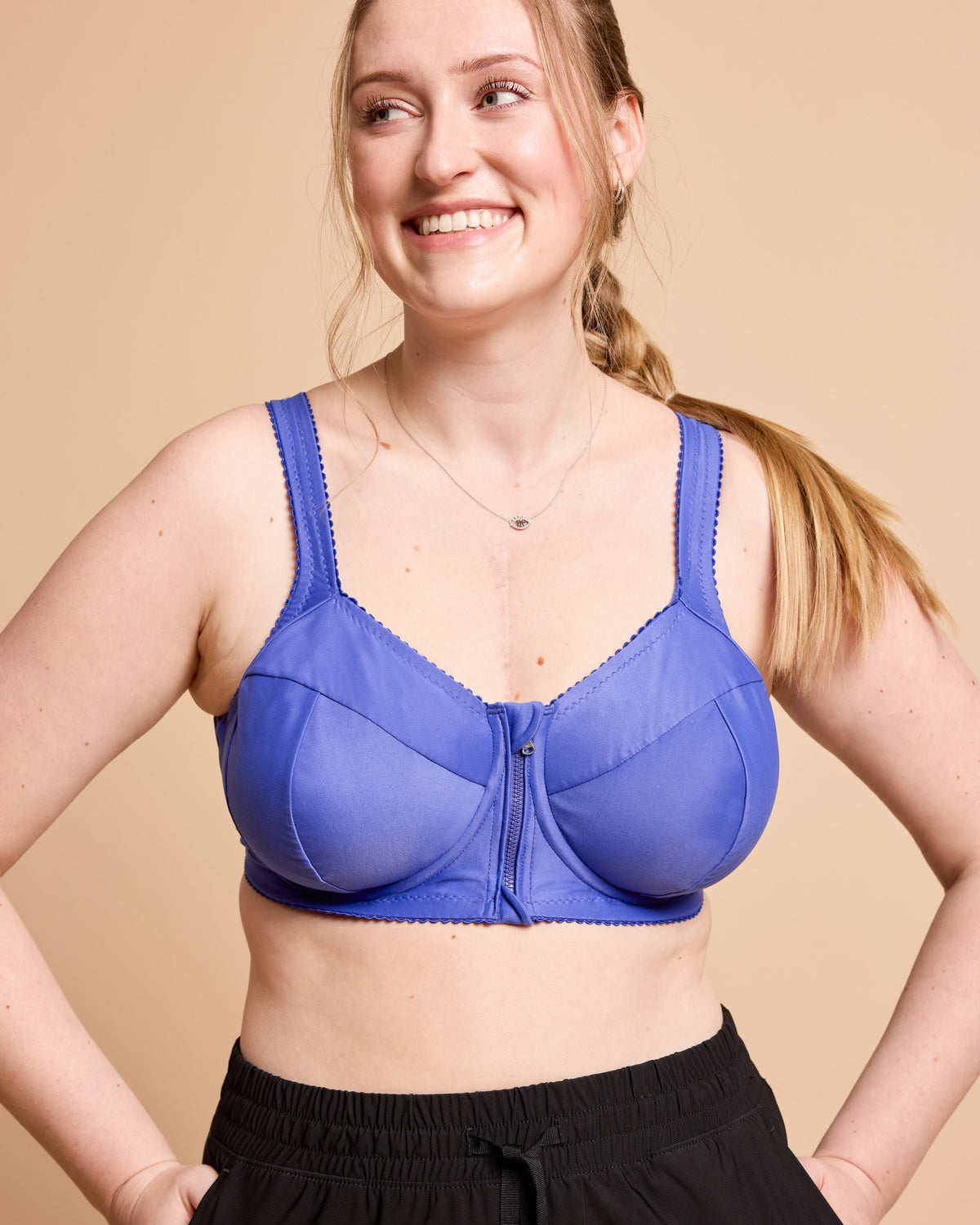 Woman wearing a blue bra against a beige background. This is the Cashmerette Somerville Sports Bra sewing pattern for big boobs.