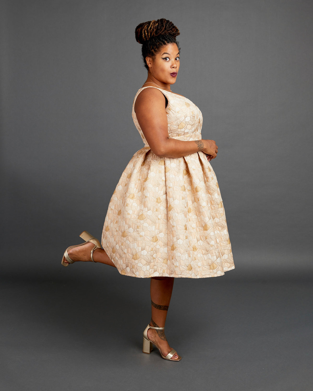 Woman wearing a beige patterned dress against a gray background. This dress is the Upton Dress & Skirt sewing pattern from Cashmerette.