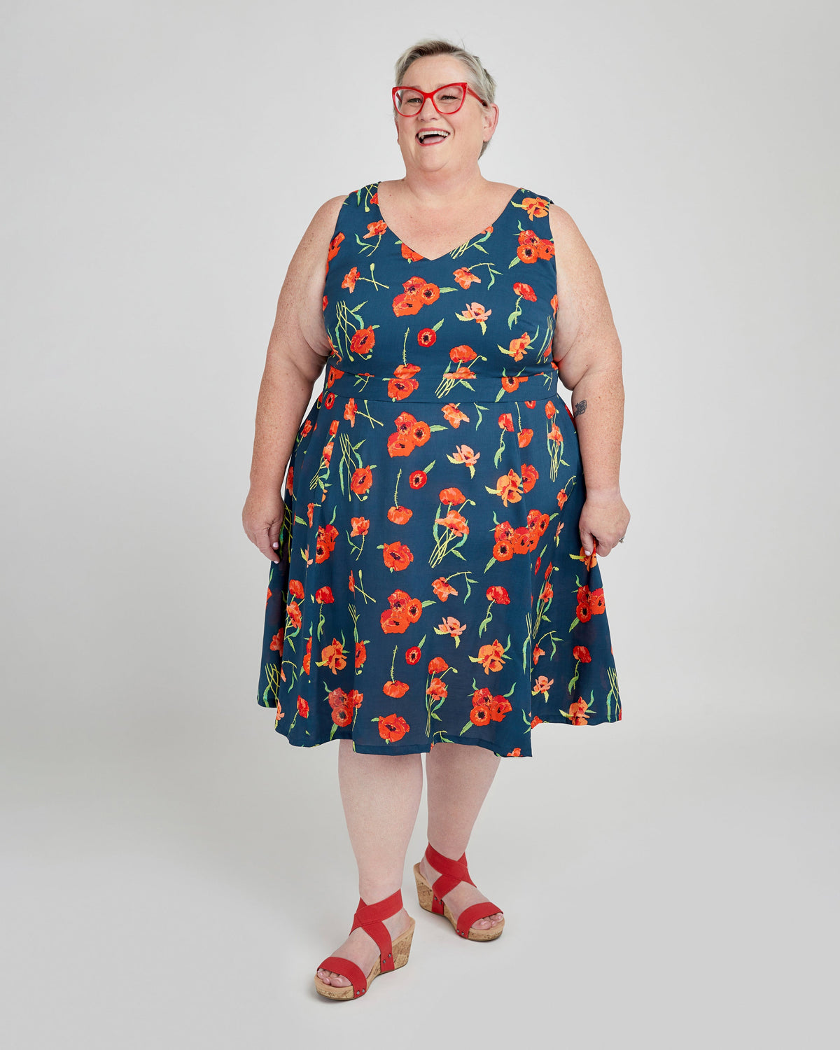 Woman wearing a blue dress with red floral pattern on a white background. This dress is the Upton Dress & Skirt sewing pattern from Cashmerette.