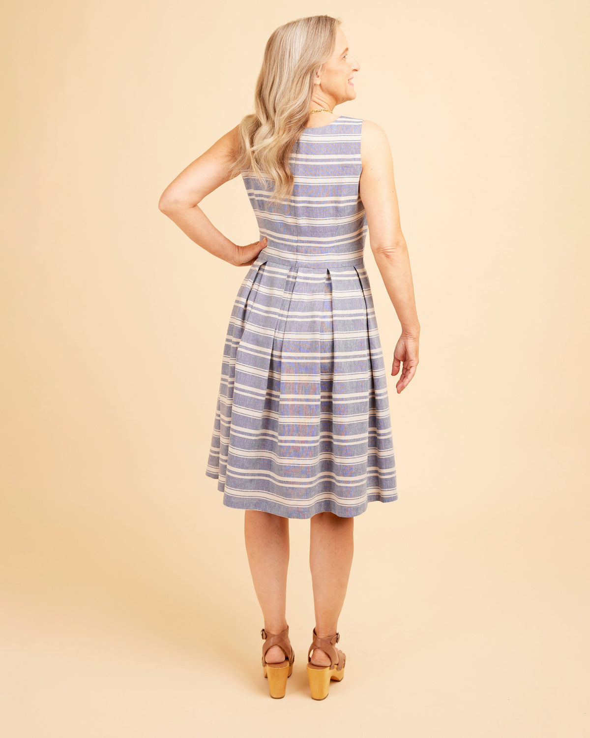 Woman wearing a blue and white striped dress against a beige background. This dress is the Upton Dress & Skirt sewing pattern from Cashmerette.