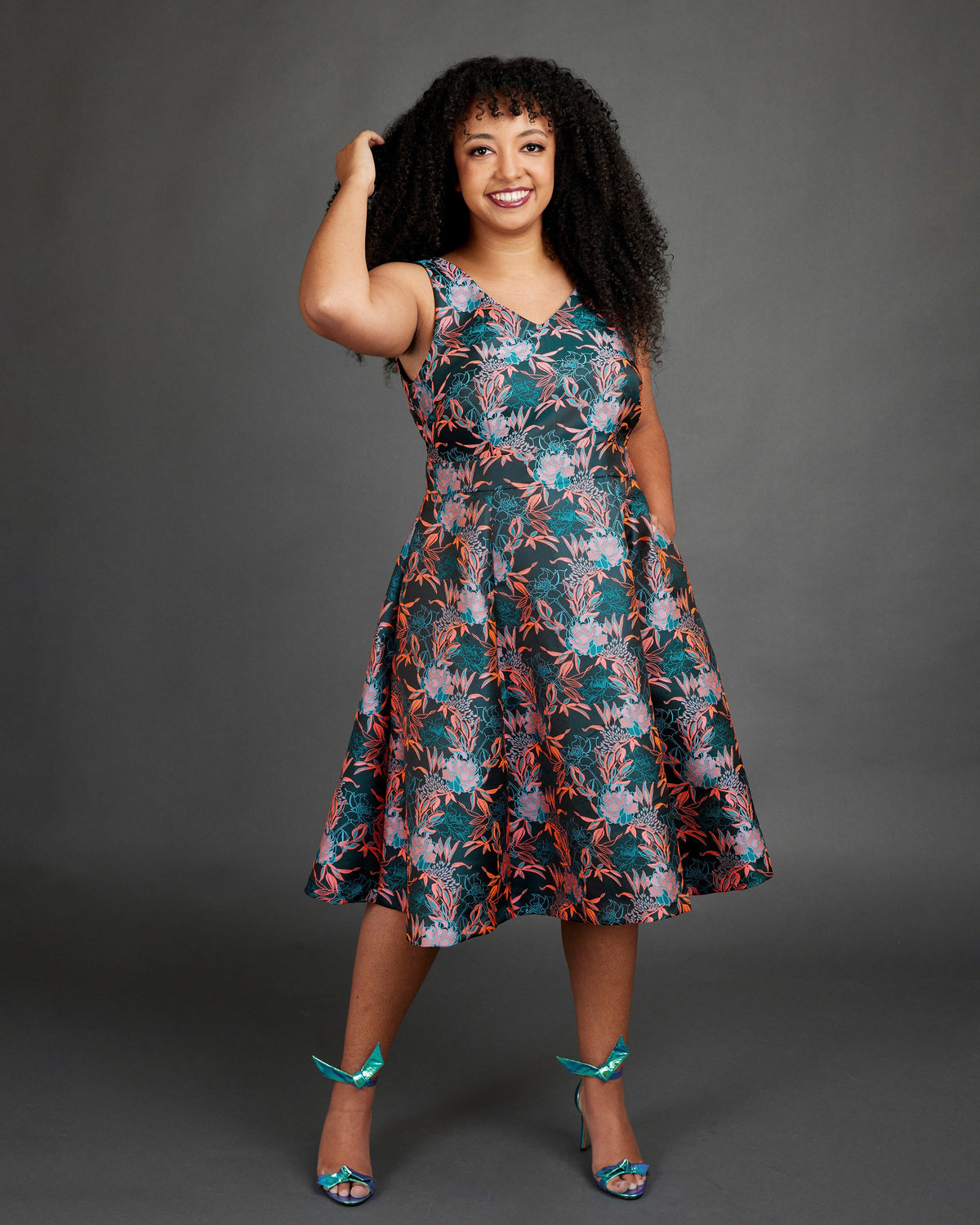 Woman wearing a floral dress against a gray background. This dress is the Upton Dress & Skirt sewing pattern from Cashmerette.