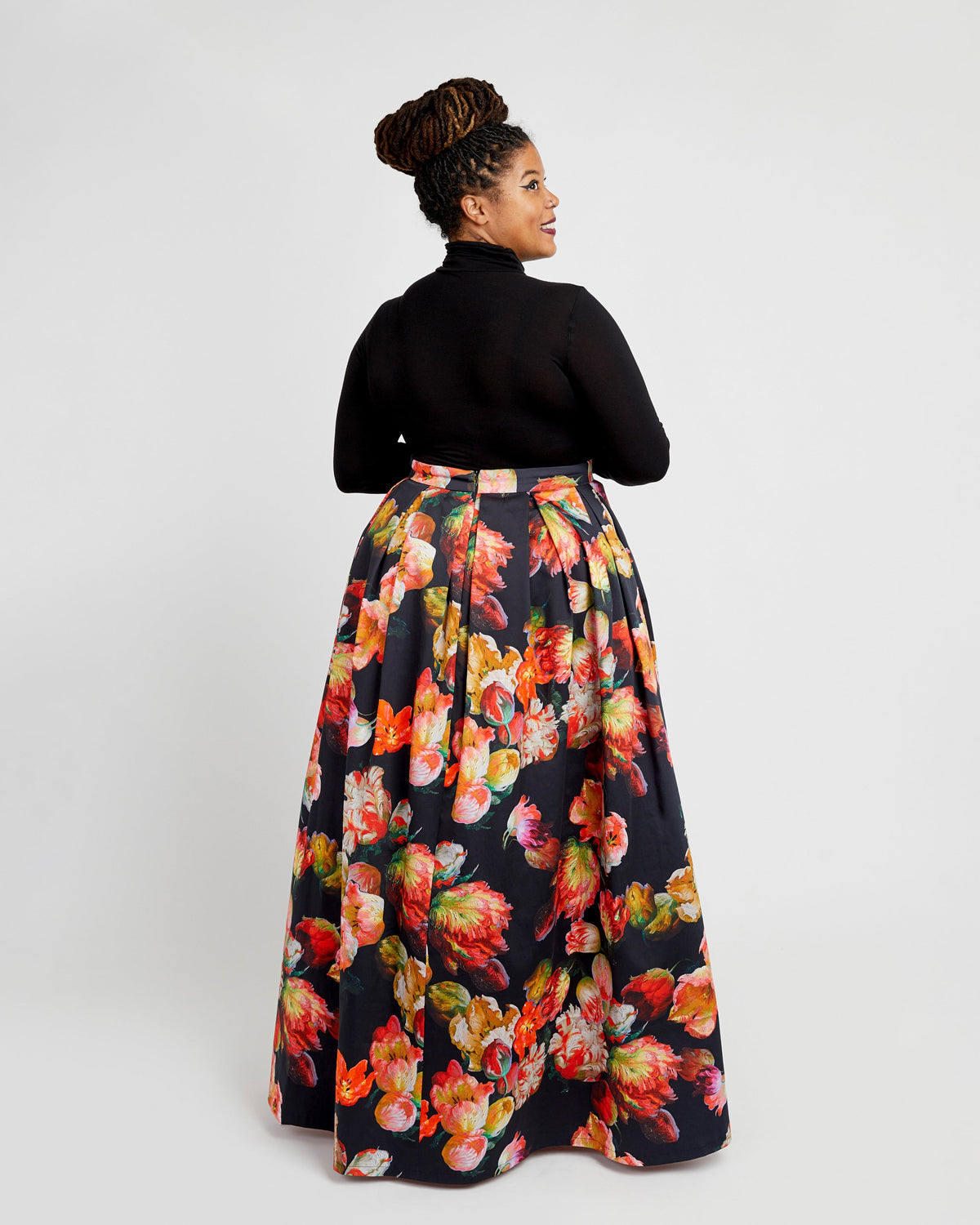 Woman wearing a black turtleneck and floral skirt on a white background. This dress is the Upton Dress & Skirt sewing pattern from Cashmerette.