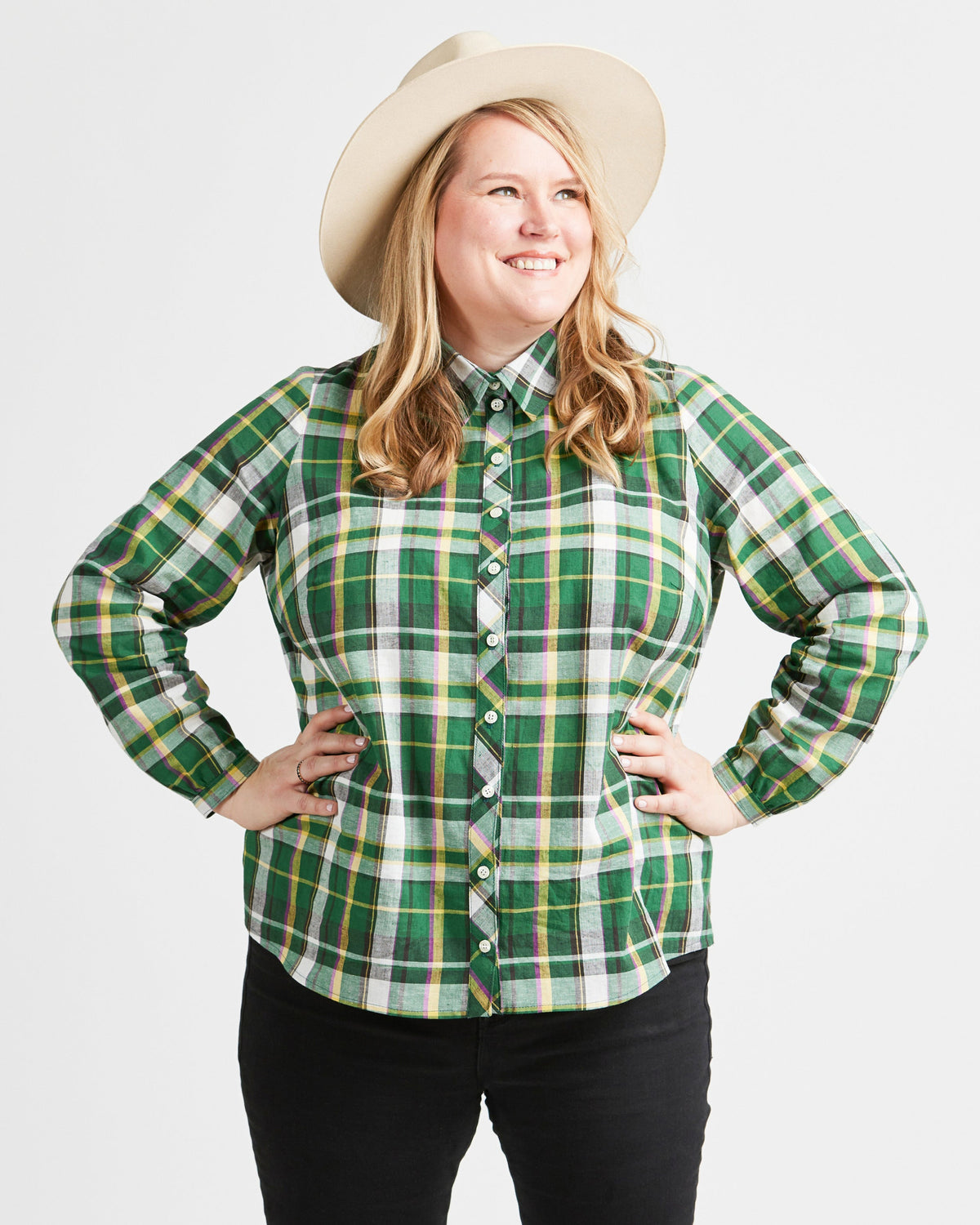 Woman wearing a green plaid shirt and a beige hat on a white background. This top is the Vernon Shirt sewing pattern from Cashmerette.