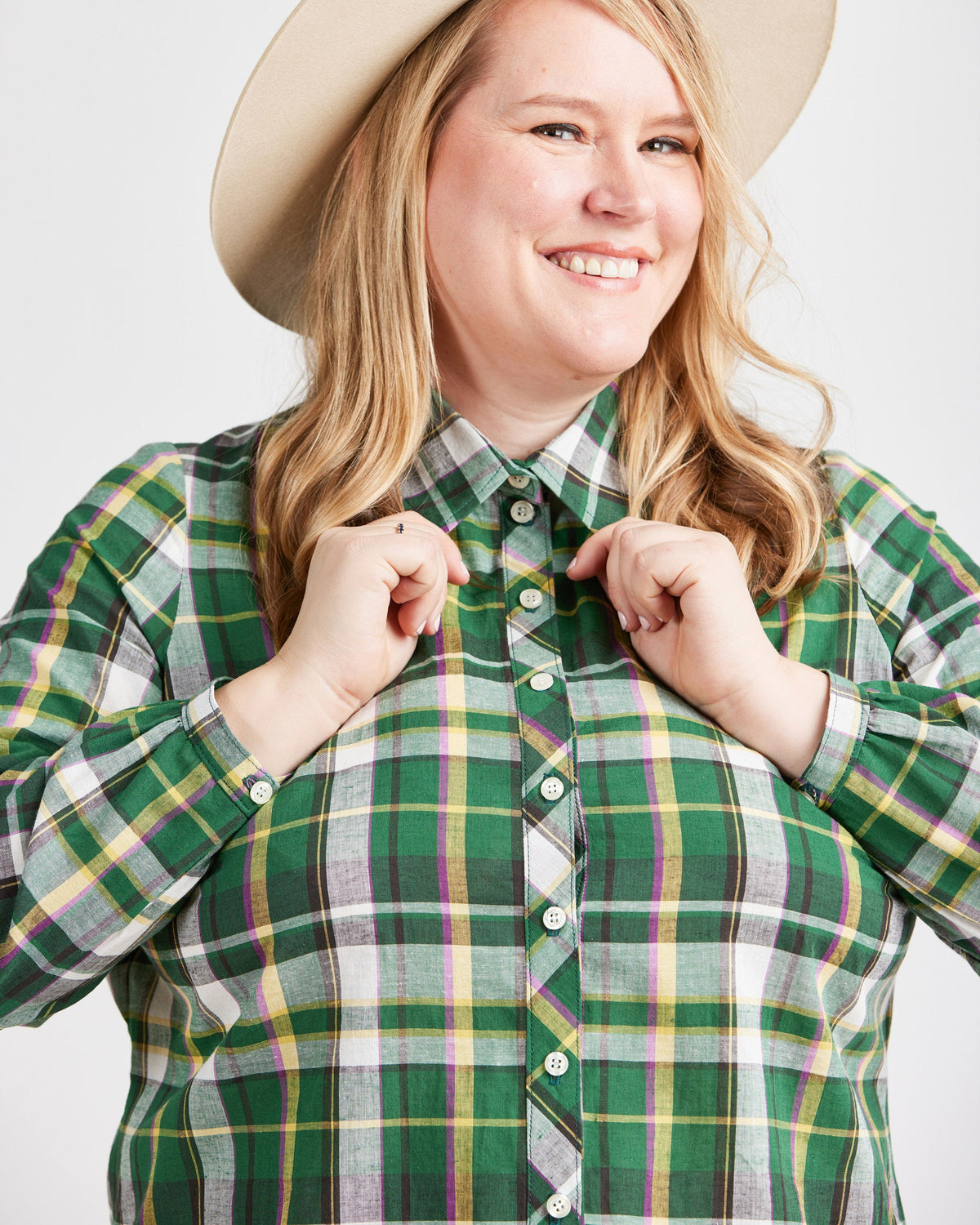 Person wearing a green plaid shirt with a beige hat on a white background. This top is the Vernon Shirt sewing pattern from Cashmerette.