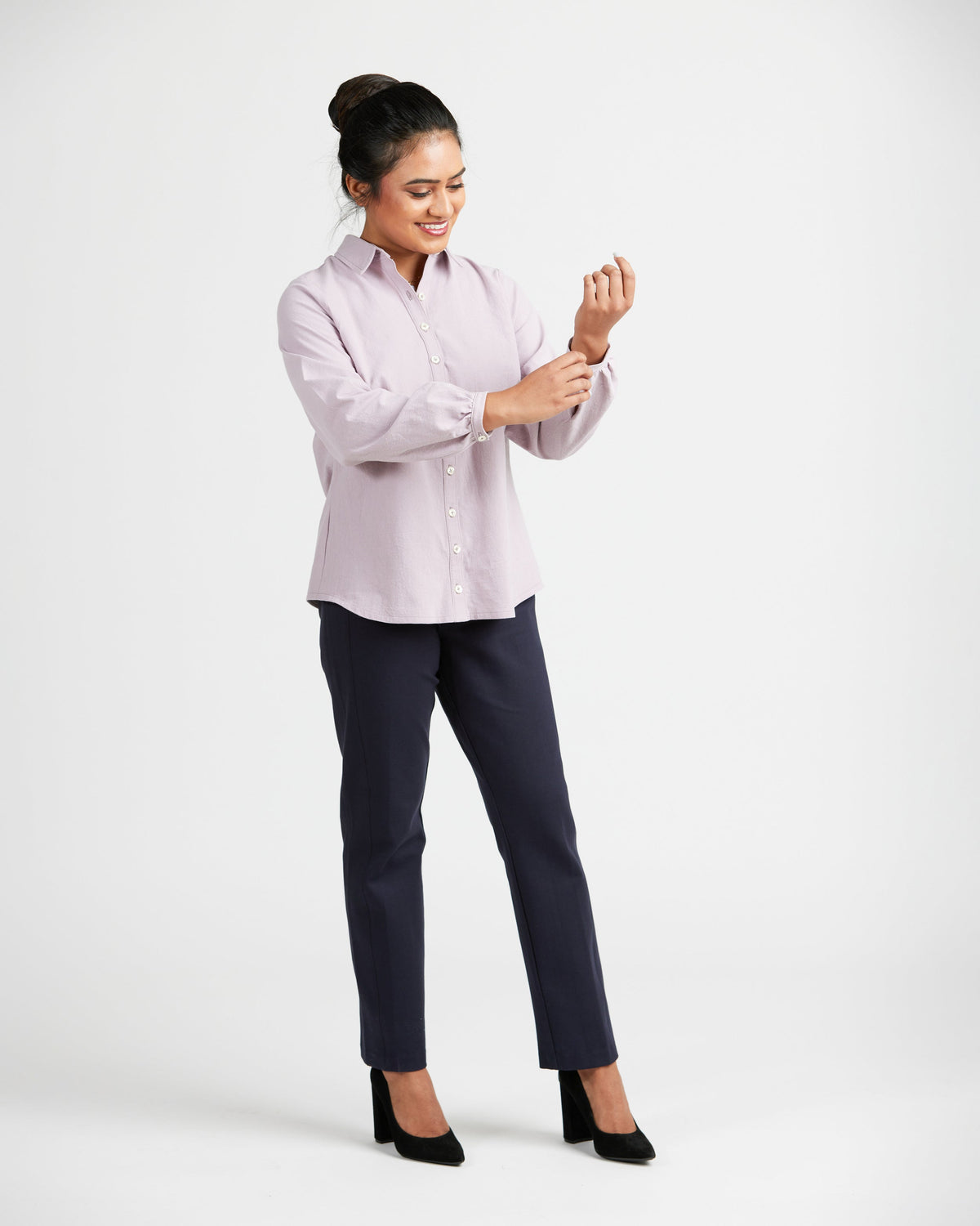 Woman wearing a light pink blouse and dark pants on a white background. This top is the Vernon Shirt sewing pattern from Cashmerette.