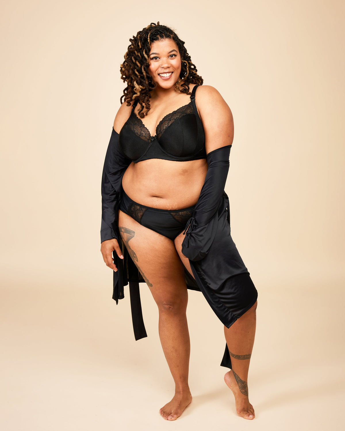 Woman wearing a black lingerie set with a beige background. This bra is the Willowdale Bra sewing pattern from Cashmerette.