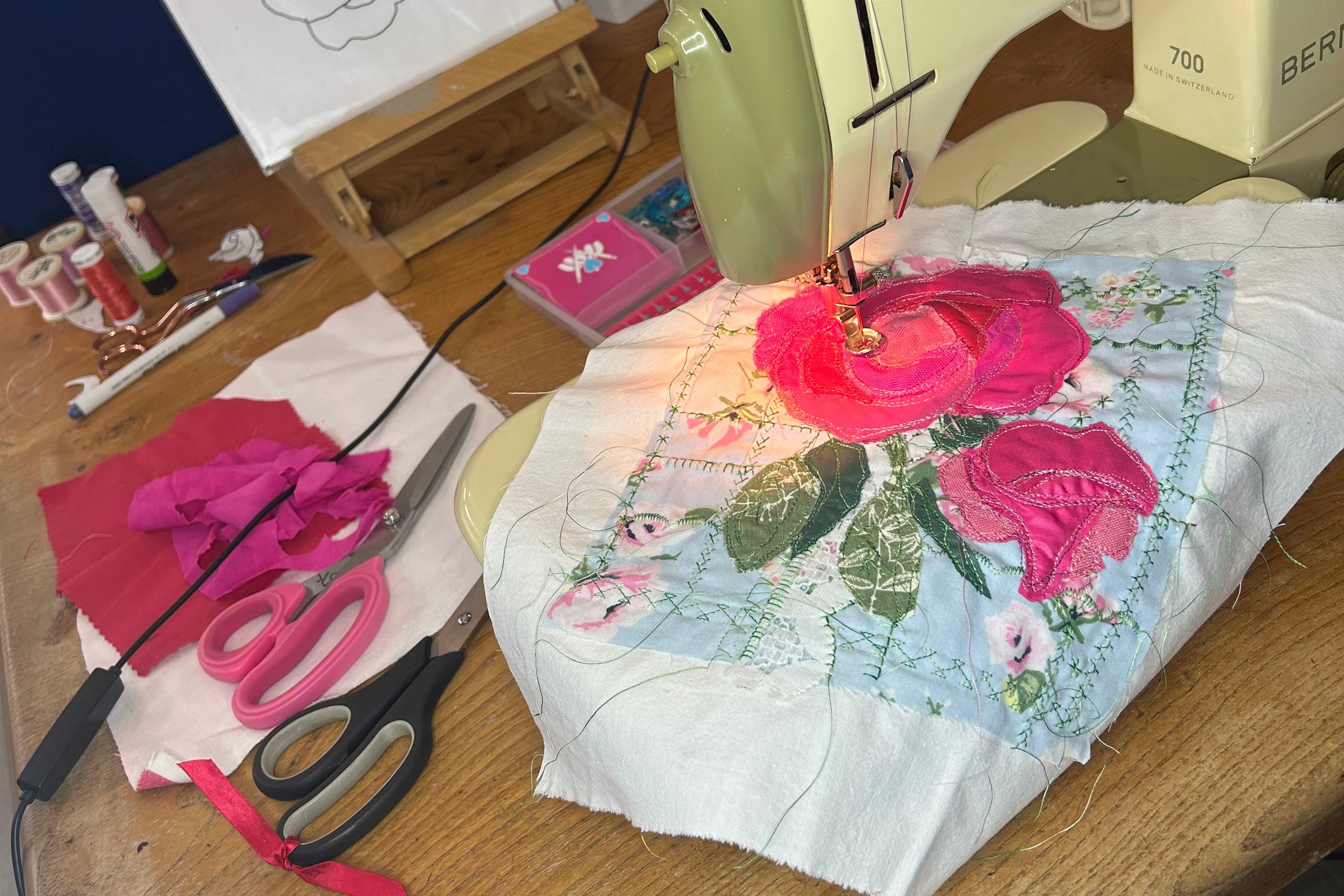 Sewing machine with a floral embroidery project on a wooden table.