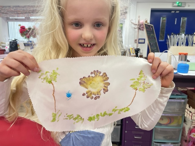 young girl proudly holds up flower pounding with embroidery